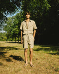 homme portant un ensemble chemise et short beige meus paris  dans un bois 