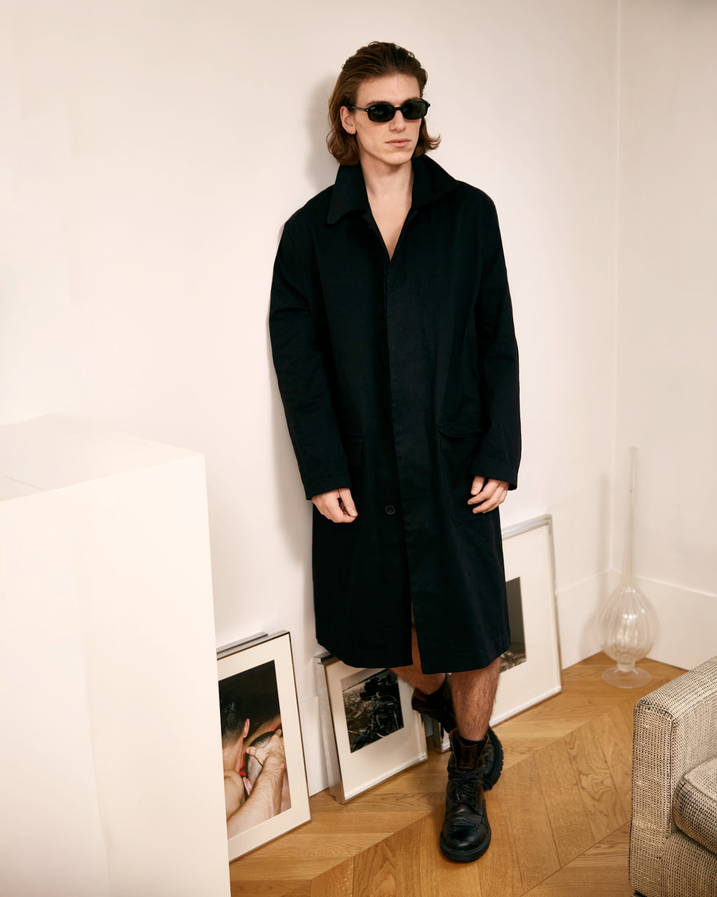 homme portant un manteau noir meus paris dans un appartement
